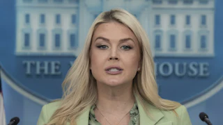 Karoline Leavitt stares from behind a podium