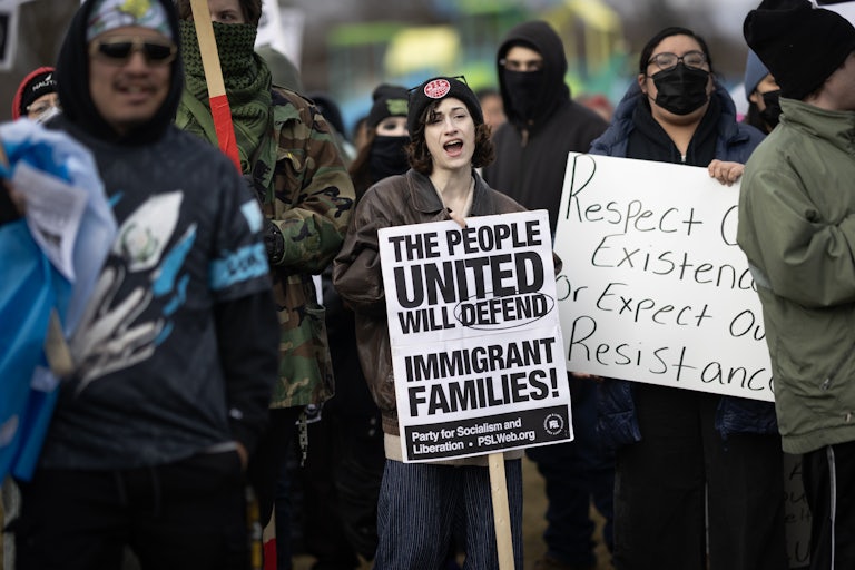 A woman protesting holds a sign that reads "The people united will defend immigrant families."
