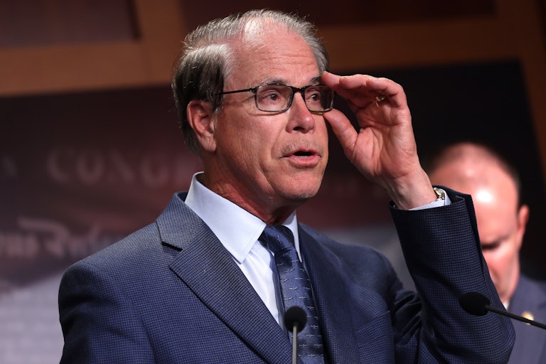 Indiana Governor Mike Braun adjusts his glasses while speaking at a podium
