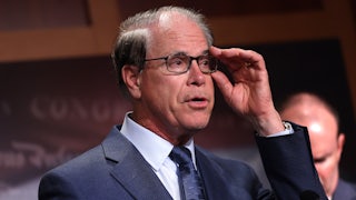 Indiana Governor Mike Braun adjusts his glasses while speaking at a podium