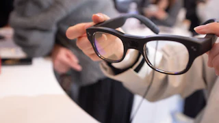 A woman holds RayNeo smart glasses