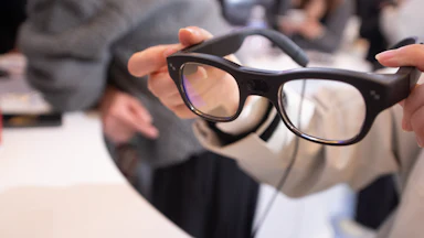 A woman holds RayNeo smart glasses