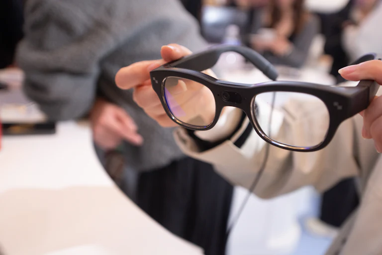 A woman holds RayNeo smart glasses