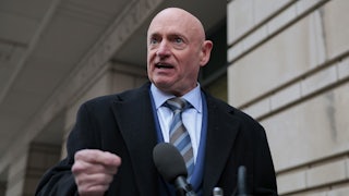 Senator Mark Kelly speaks at a lectern outdoors.