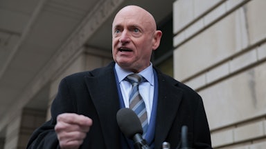 Senator Mark Kelly speaks at a lectern outdoors.