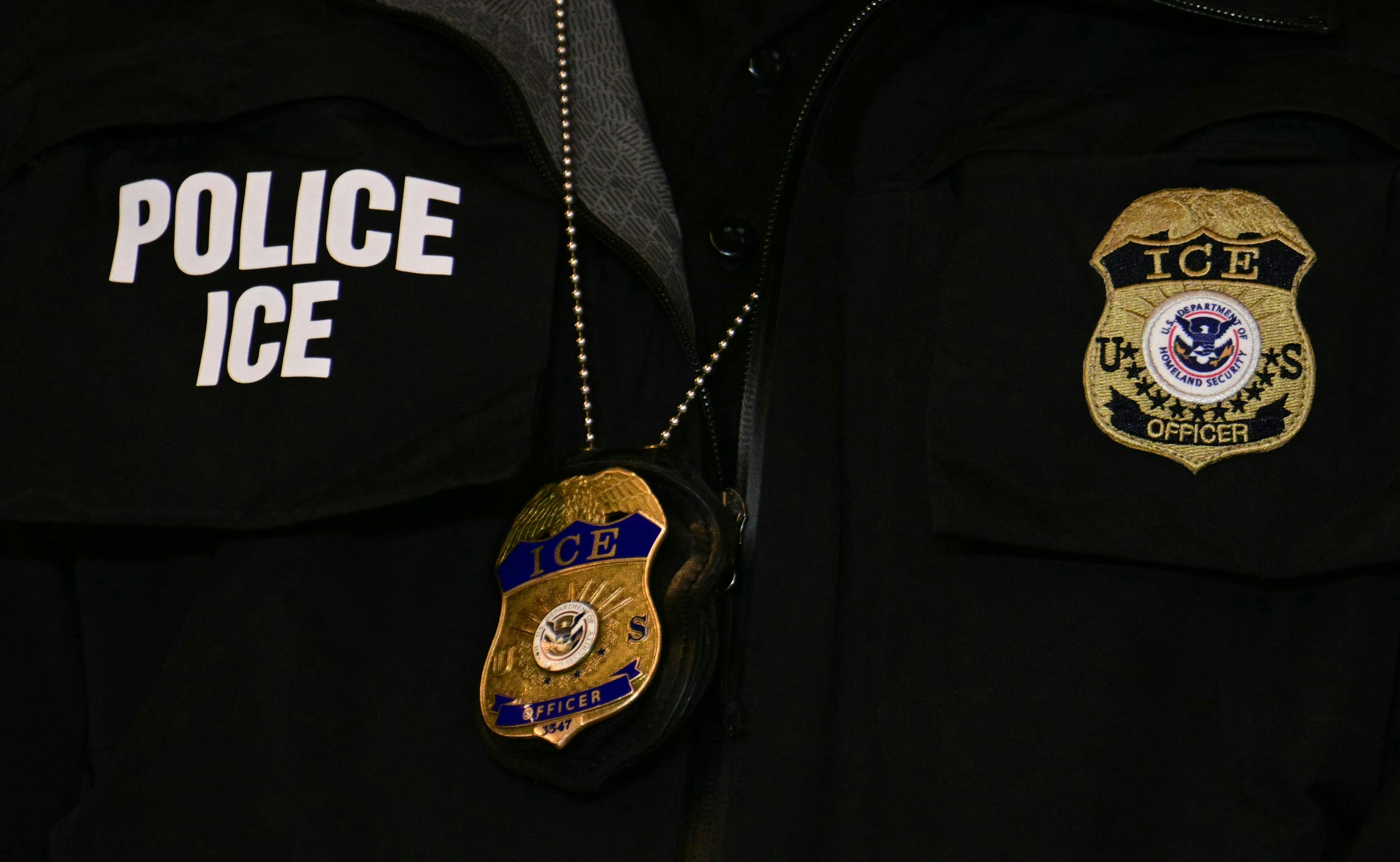 A close-up of an ICE agent's vest and badge