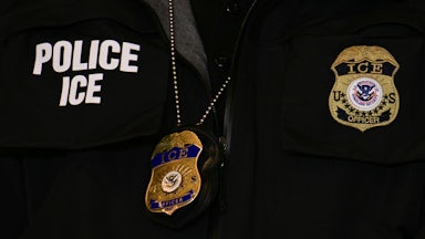 A close-up of an ICE agent's vest and badge