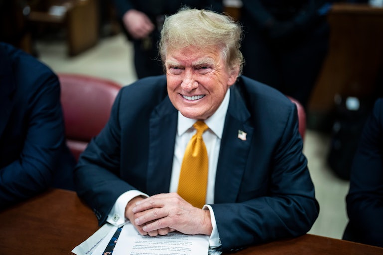 Donald Trump smiles while sitting in a courtroom