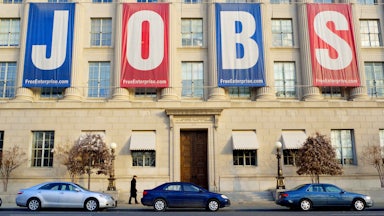 A pedestrian passes under a large banner reading "JOBS" outside of the Chamber of Commerce in Washington, DC.