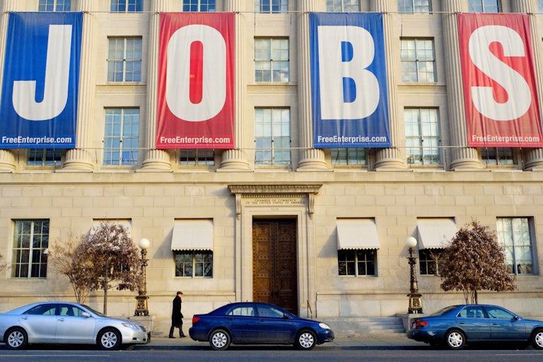 A pedestrian passes under a large banner reading "JOBS" outside of the Chamber of Commerce in Washington, DC.