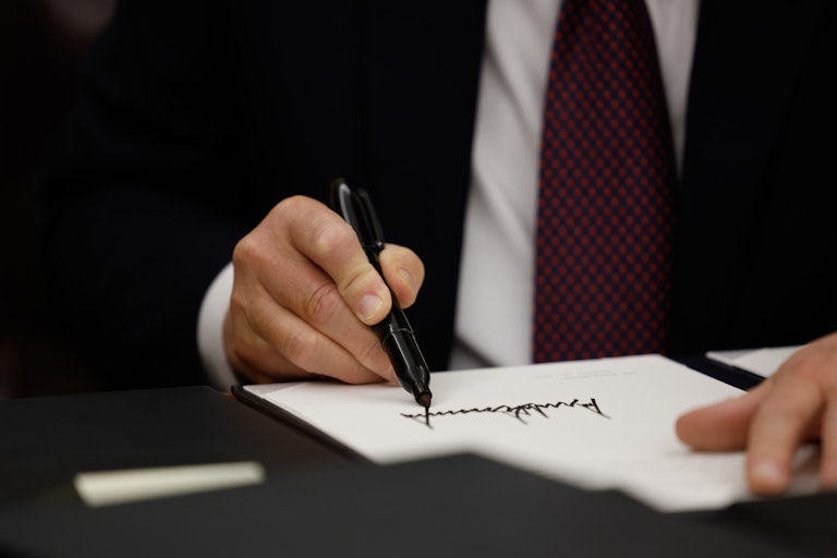 Zoom-in on Donald Trump’s hand as he signs an executive order in a black marker