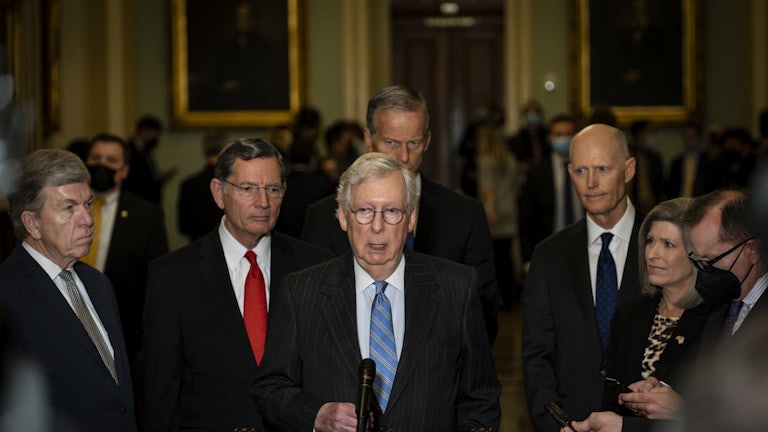 Senate Minority Leader Mitch McConnell stands at a lectern flanked by his Republican colleagues.
