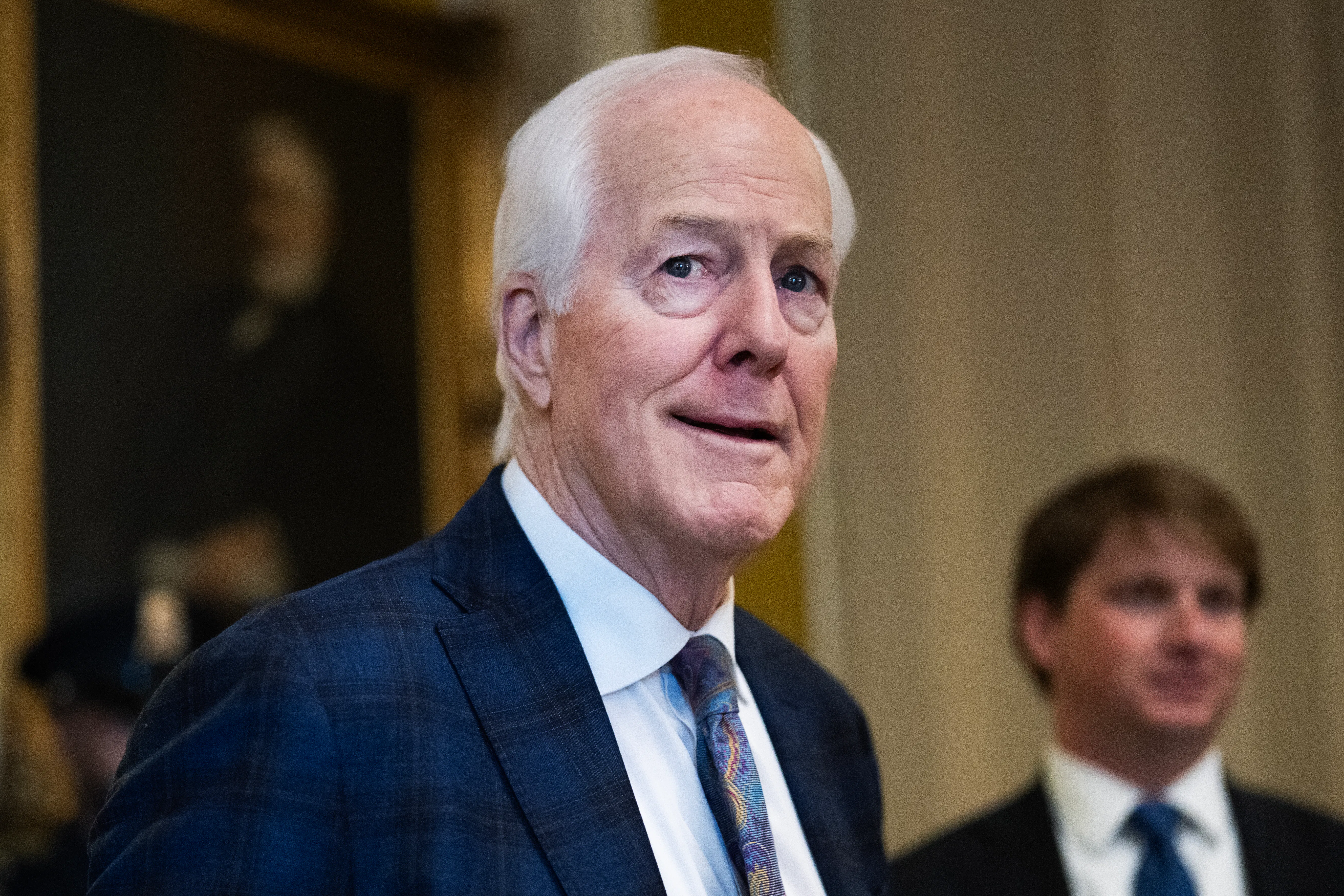 Senator John Cornyn looks to the side while walking in the Capitol