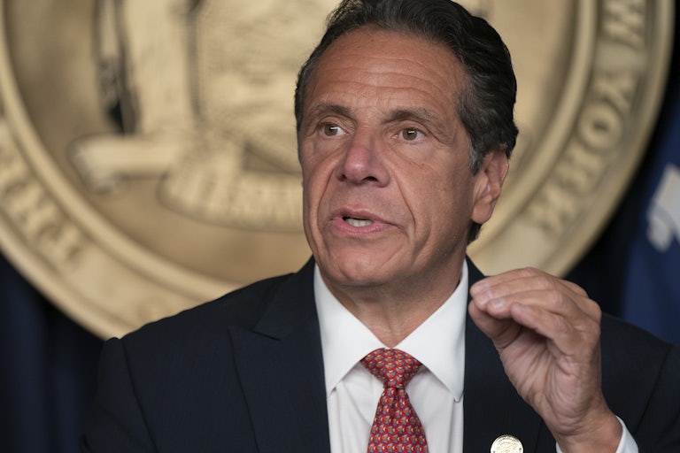 Andrew Cuomo, wearing a suit, speaks and gestures with his hand