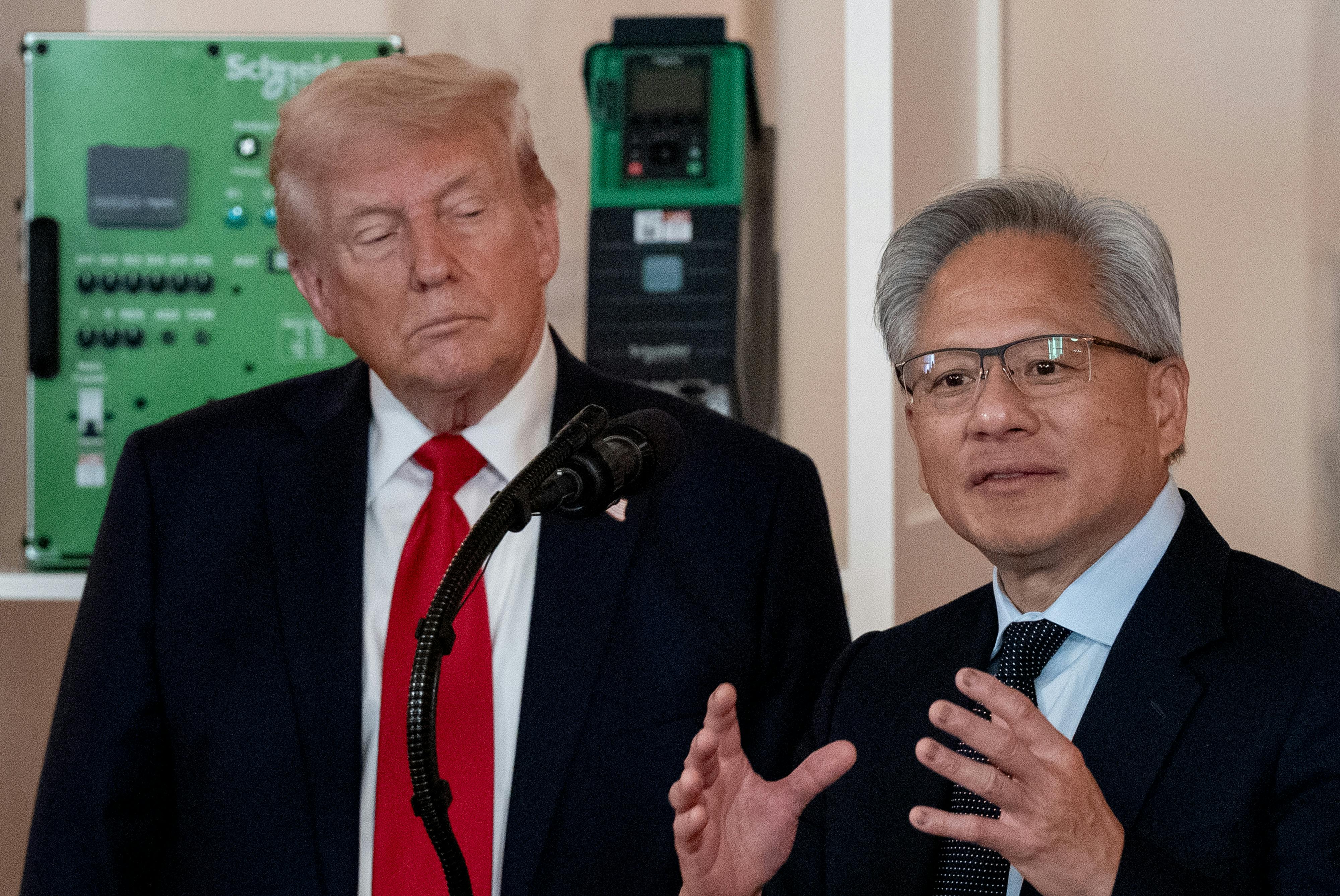 Donald Trump watches as Nvidia CEO Jensen Huang gestures and speaks at a podium