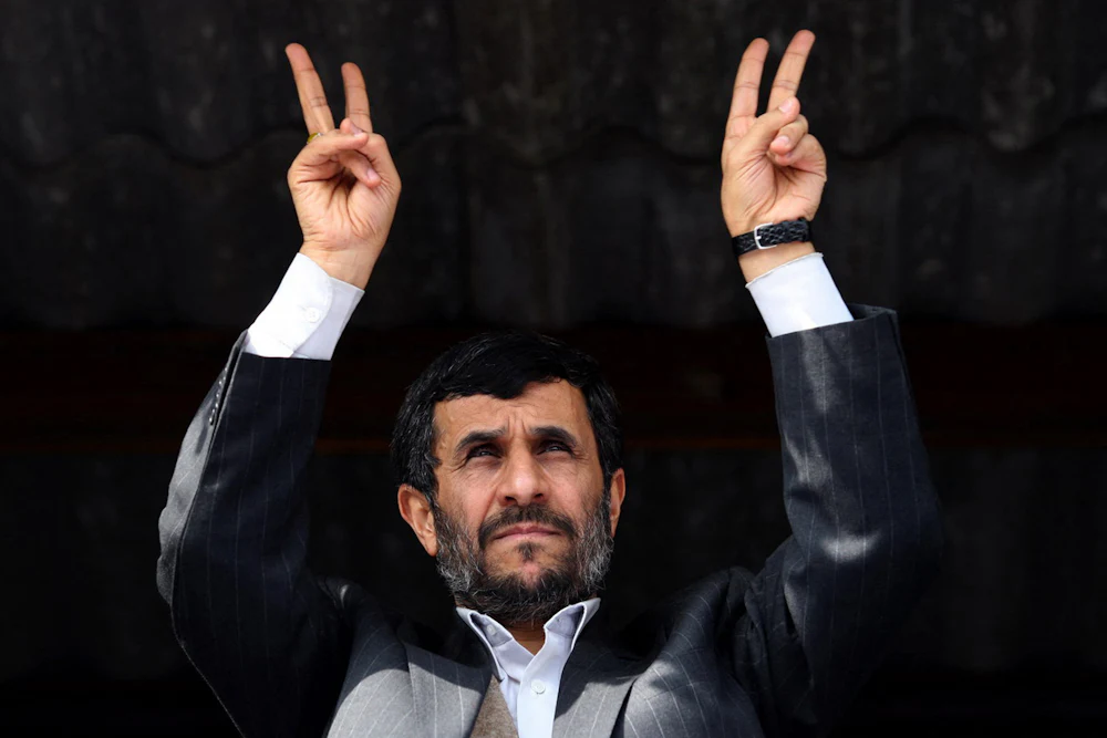 Mahmoud Ahmadinejad holds up a double V