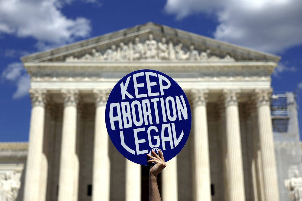 A pro-abortion protester holds up a sign reading "Keep Abortion Legal" in front of the Supreme Court
