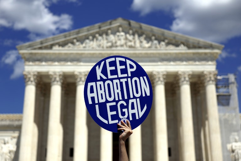 A pro-abortion protester holds up a sign reading "Keep Abortion Legal" in front of the Supreme Court