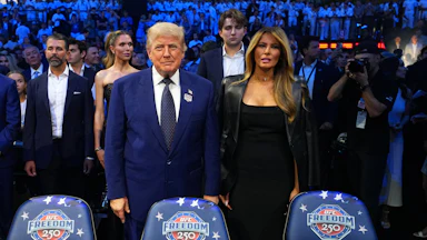 Donald Trump stands next to Melania Trump. They do not hold hands.