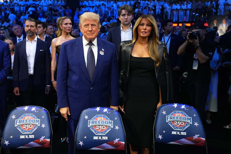 Donald Trump stands next to Melania Trump. They do not hold hands.