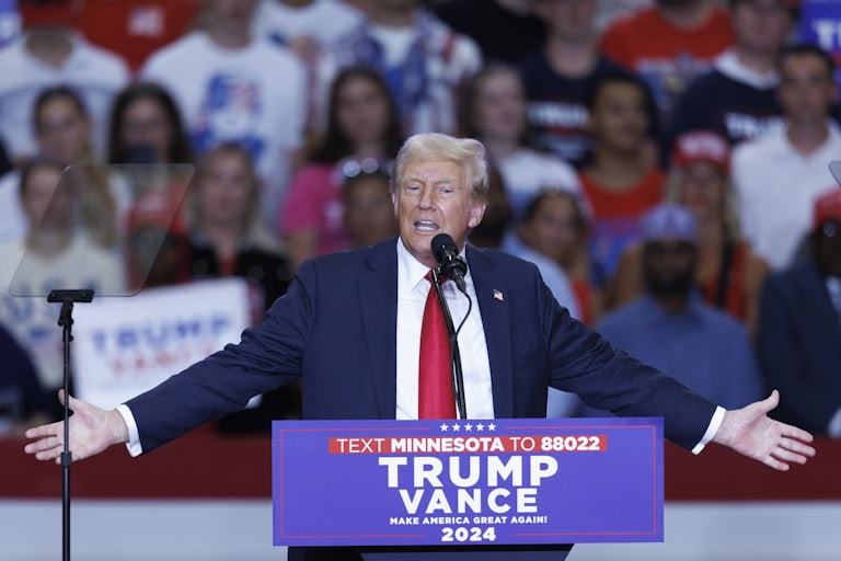 Donald Trump holds his arms out while speaking at a rally