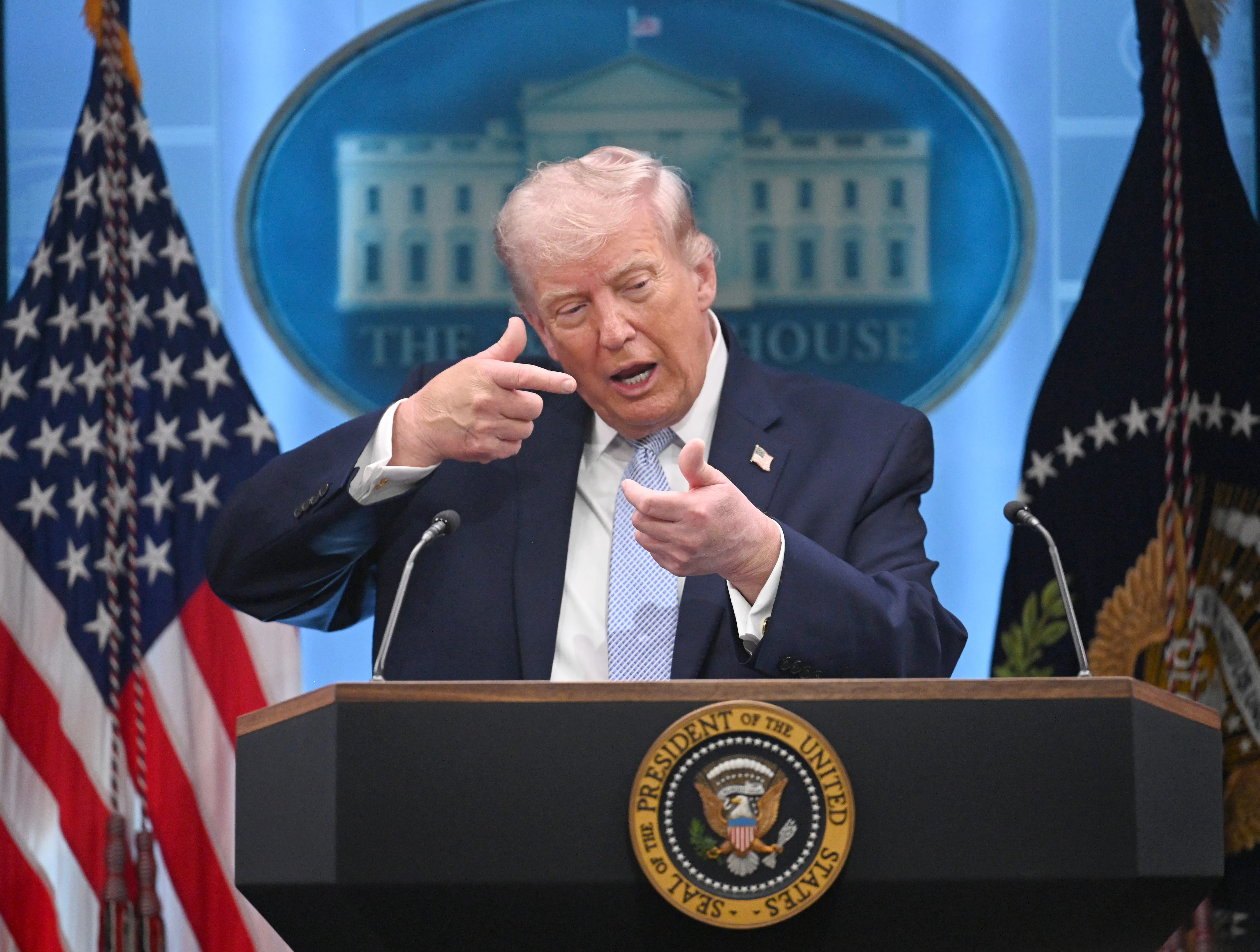 Donald Trump mimes aiming a gun while speaking at a podium