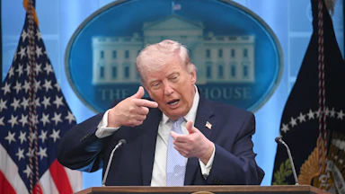 Donald Trump mimes aiming a gun while speaking at a podium