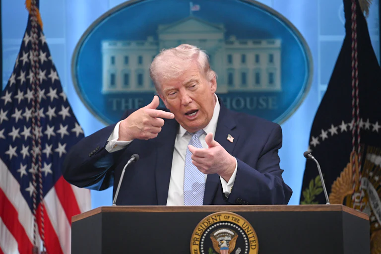 Donald Trump mimes aiming a gun while speaking at a podium