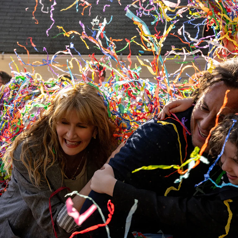 Confetti falling over the faces of Laura Dern, Will Arnett, and Calvin Knegten in Bradley Cooper’s “Is This Thing On?”