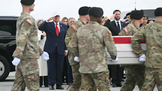 Donald Trump and JD Vance stand as military servicemembers escort the remains of fallen soldiers in front of them.