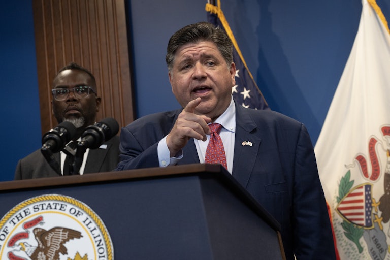 Chicago Mayor Brandon Johnson listens as Illinois Governor JB Pritzker speaks.