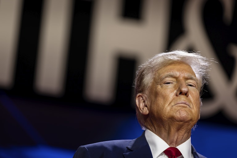 Donald Trump stands in front of a background that reads "FAITH." He looks grim.