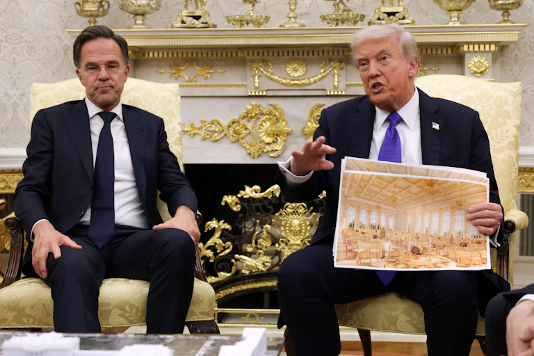 Trump holds an architectural rendering in front of a man who seems exasperated
