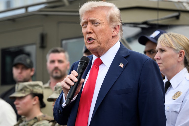 Donald Trump speaks into a hand-held microphone while surrounded by troops in Washington, D.C.
