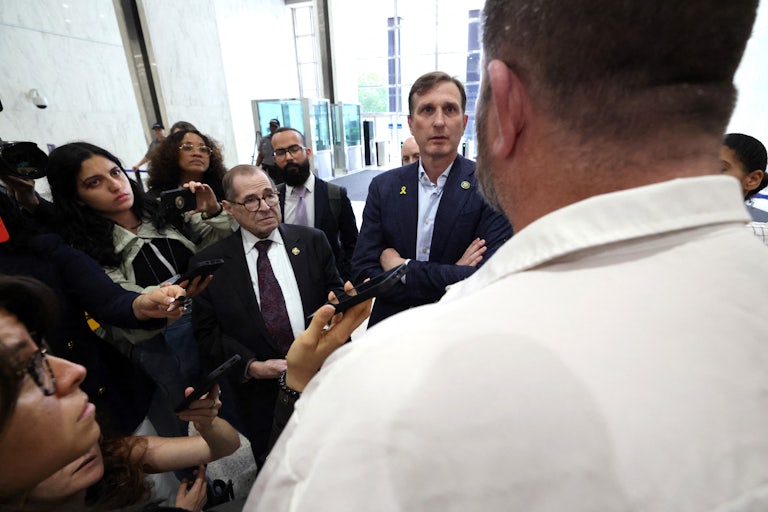 Representatives Jerry Nadler and Dan Goldman are surrounded by reporters as they stand in the lobby of a building, attempting to enter an ICE facility