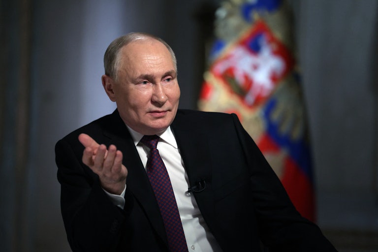 Vladimir Putin speaks and raises his hand as if in question