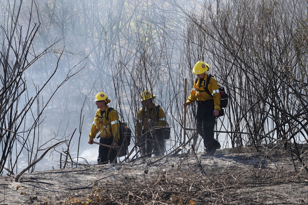 On July 6, three firefighters in yellow helmets walked through brush as they battled a wildfire in Montebello, California.
