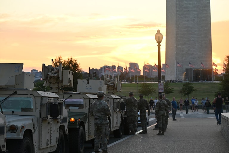 Members of the National Guard stand next to military vehicles parked by the Washington Monument