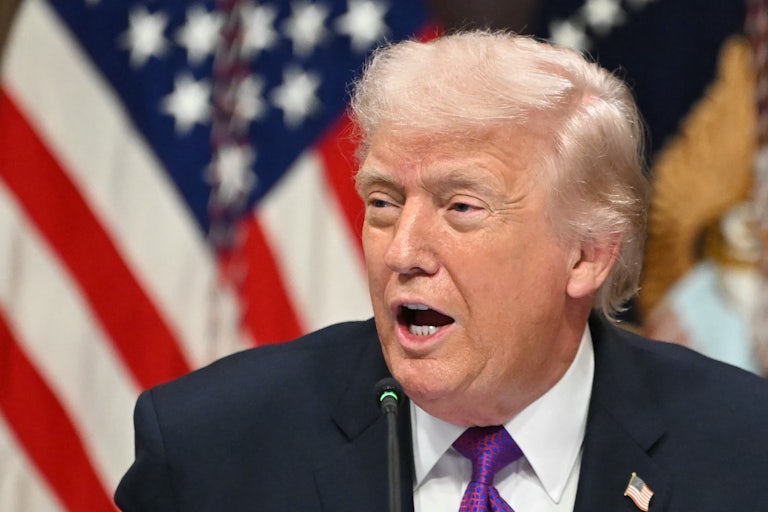 Donald Trump turns his head to the side while speaking into a microphone