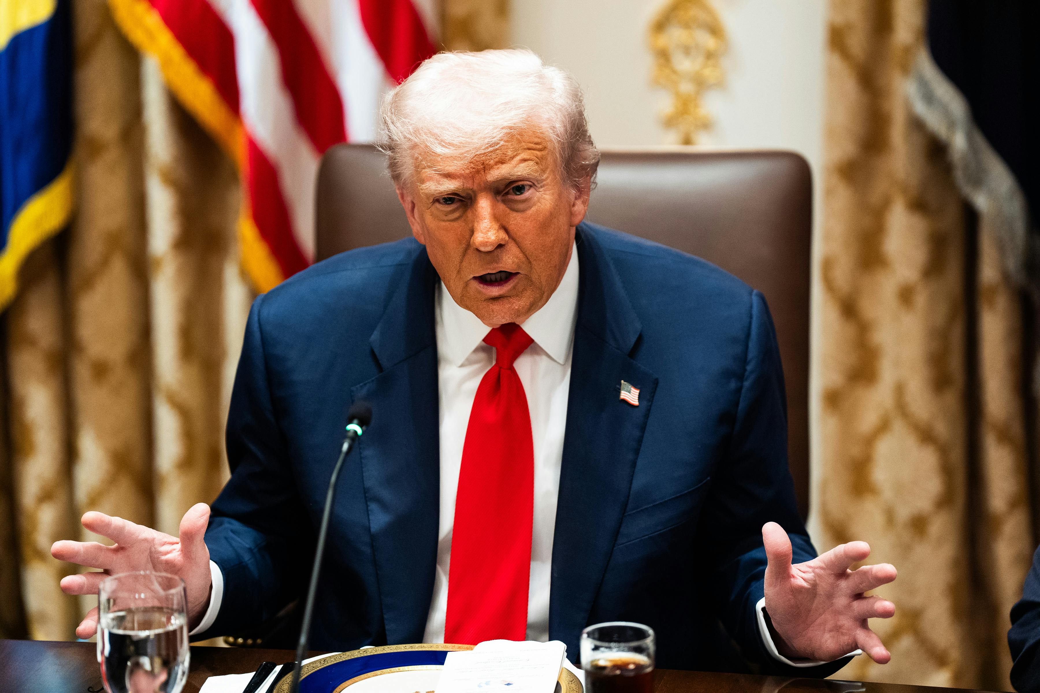 Donald Trump gestures with both hands while speaking into a microphone