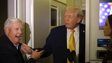 Senator Lindsey Graham and Donald Trump stand next to each other while speaking to reporters on Air Force One.
