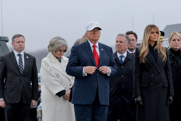 Donald Trump adjusts his suit while standing during a dignified transfer ceremony
