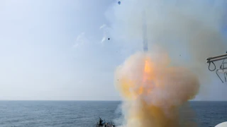 A Tomahawk land attack missile is launched in the sea amid a cloud of smoke.