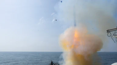 A Tomahawk land attack missile is launched in the sea amid a cloud of smoke.