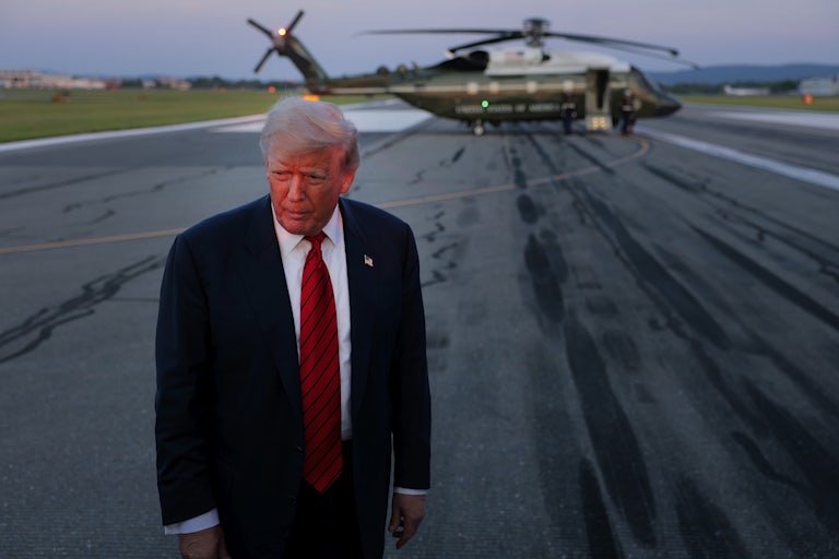 Donald Trump stands on a tarmac in front of the Marine One helicopter