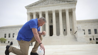 Former Bremerton High School assistant football coach Joe Kennedy takes a knee in front of the U.S. Supreme Court after his legal case, Kennedy vs. Bremerton School District, was argued before the court.