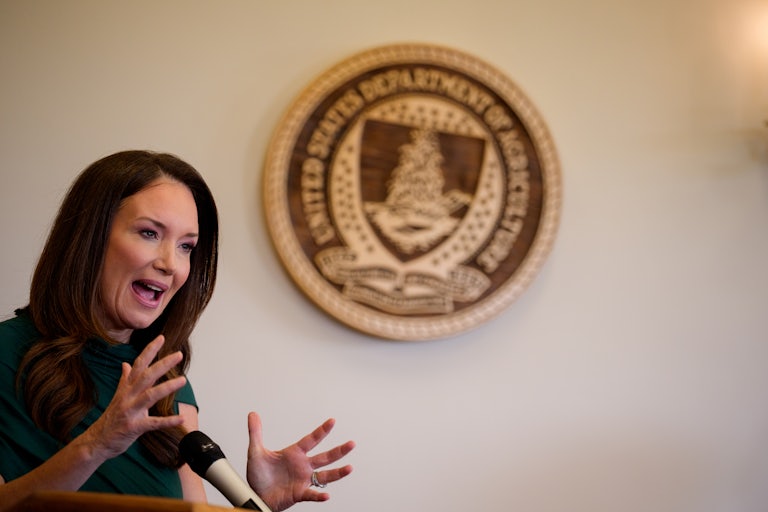 Agriculture Secretary Brooke Rollins gestures while speaking. The Department of Agriculture seal is on the wall behind her.