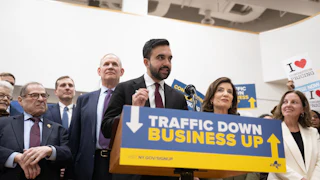 Zohran Mamdani, Kathy Hochul, and several others stand behind a podium reaching "Traffic Down. Business Up."