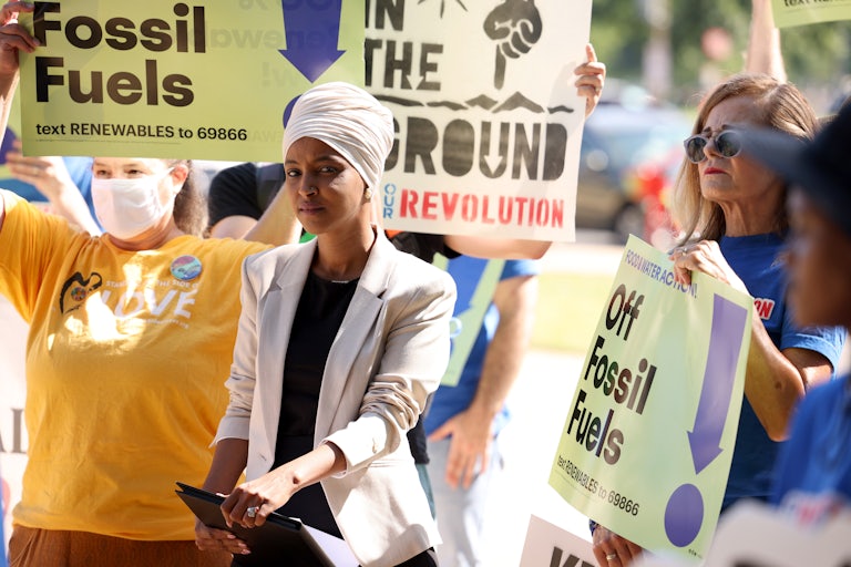 Ilhan Omar stands in front of protesters.