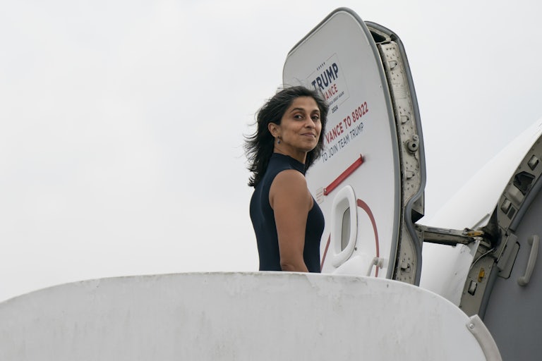Usha Vance boards a Trump-Vance plane as she looks at the camera.